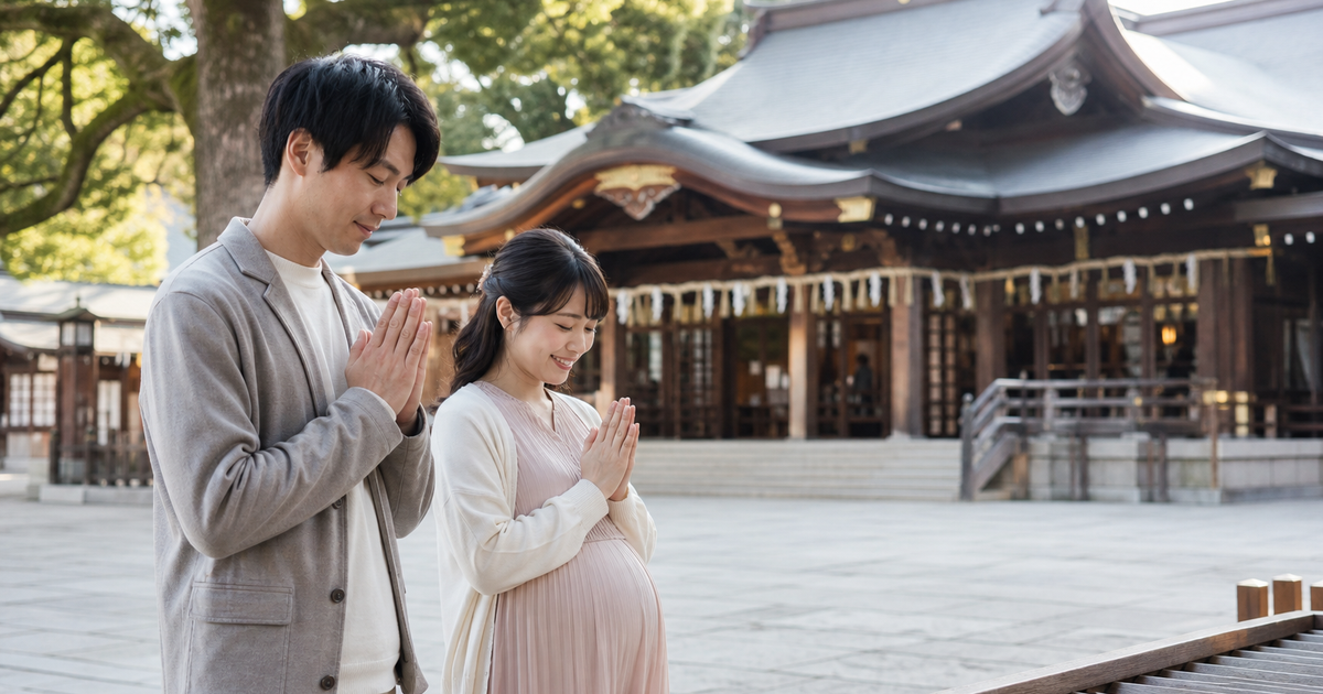 神社の拝殿の前で安産を祈る妊婦さんと夫